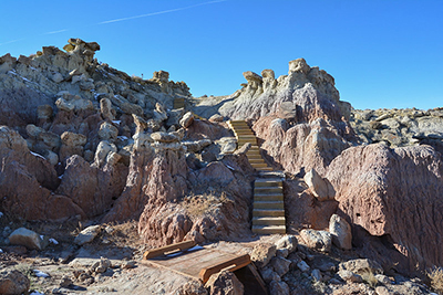 Set of wooden stairs lead through path of red rocks. 