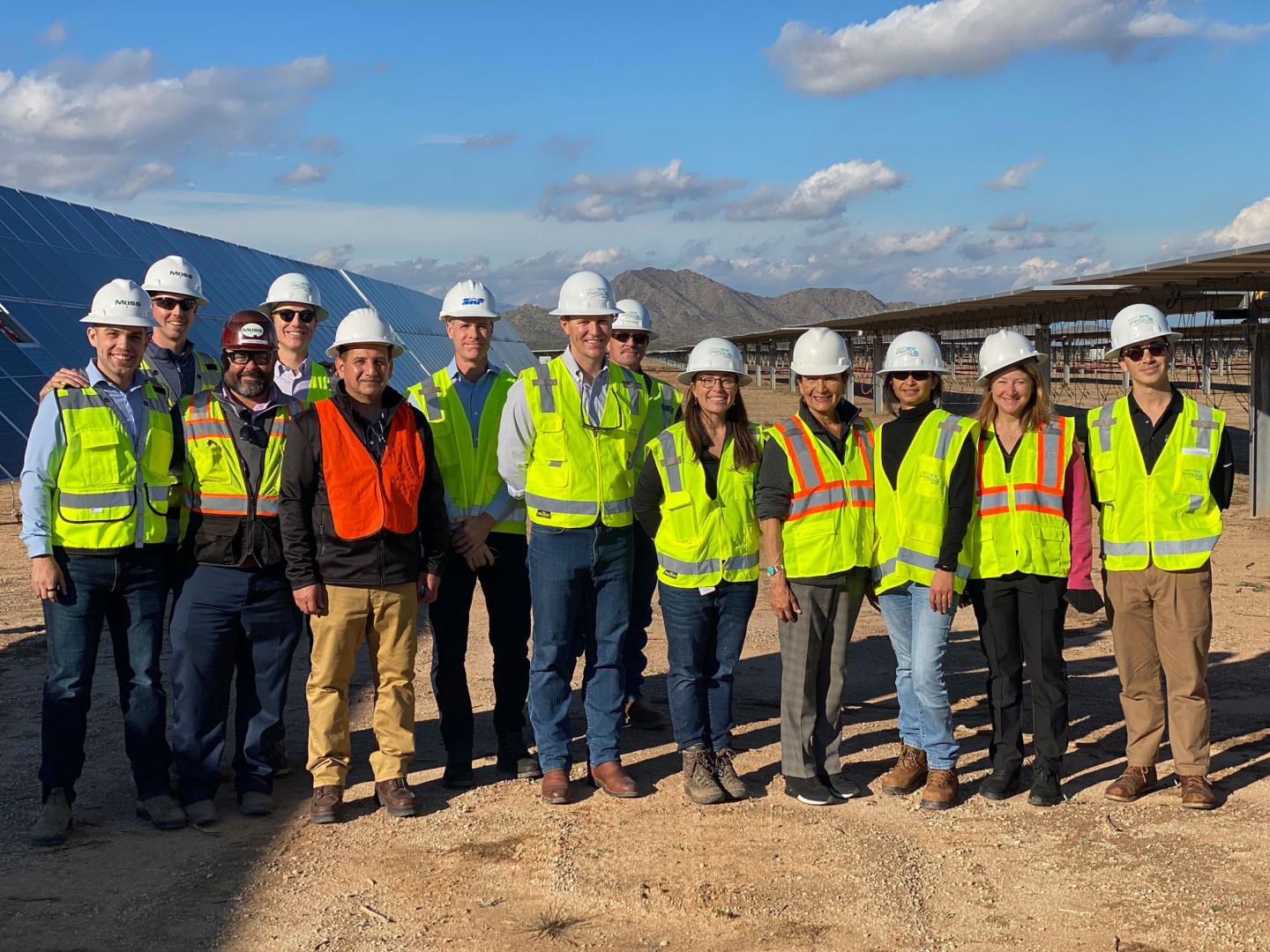 Group of people wearing hard hats and safety vests.