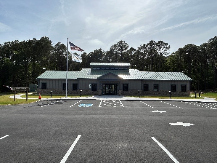  New building with a parking lot in front and an American flag blowing in the wind.