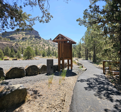 Wooden kiosk with paved walkway and mountain range in the background
