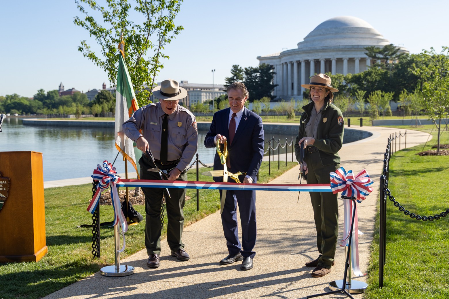 Secretary Burgum and two park rangers cutting red white and blue ribbon at ribbon cutting ceremony. 
