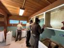 Three MAT members hang cabinets in a room with green walls and board ceiling.