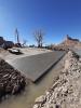 Construction vehicles sit on a concrete boat ramp surrounded by rocks.