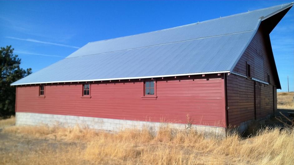 Newly rehabilitated historic barn with red siding and blue roof.