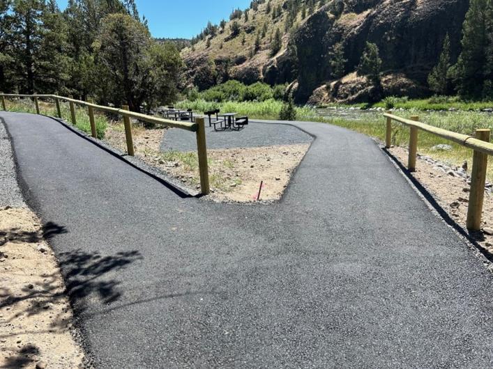 A paved path with handrails leading to a picnic table.