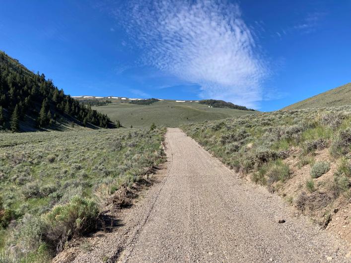Aggregate road surrounded by green hilly landscape.