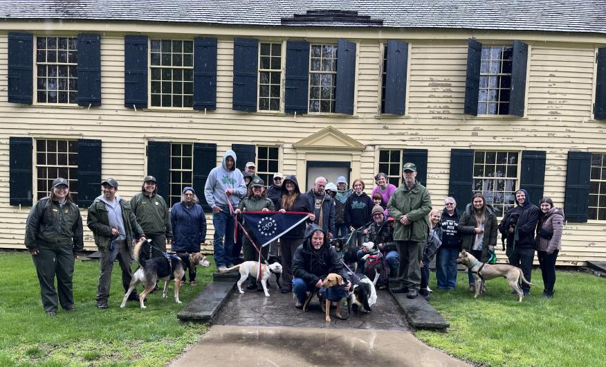 Park and Bark rangers at Saratoga NHP standing in front of building holding commemorative flag. 