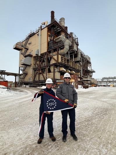 Two people in hard hats holding the commemorative flag