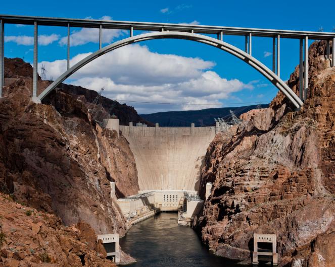 Hoover Dam and the bypass bridge under a partially-cloudy sky.