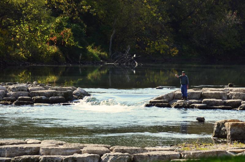 Person fly fishing on a rushing river.