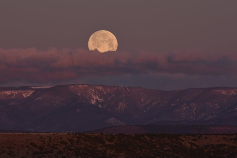 Purple clouds hover above snowy mountains at Rio Mora National Wildlife Refuge.