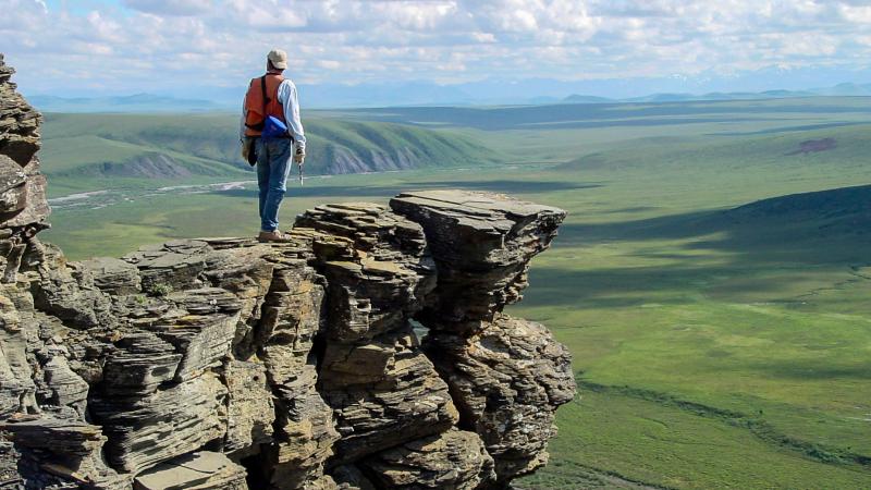 A geologist stands on​ an o​utcrop of Nanushuk Formation, Tuktu Bluff​, Alaska