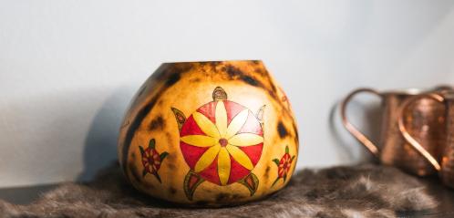 Photograph of a gourd painted with a turtle and floral motif.