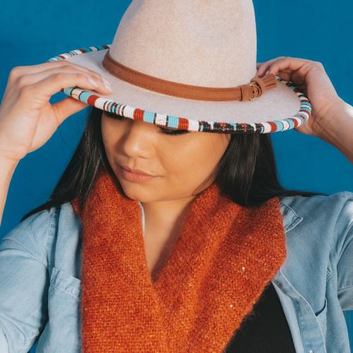 Woman wearing tan hat with a striped beaded rim.