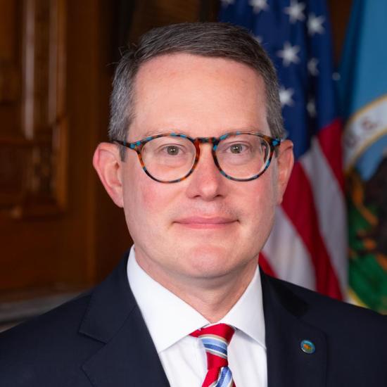 Portrait of Troy Finnegan in suit and red white and blue striped tie. 