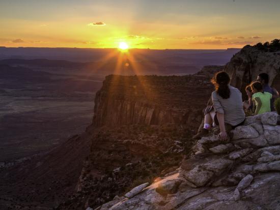 Hikers enjoy the sunset from a cliff overlooking a valley