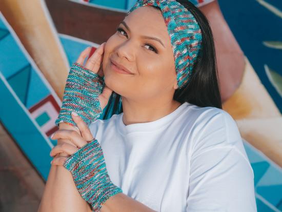 Photograph of woman posing wearing blue knitted hand warmers and a head band.