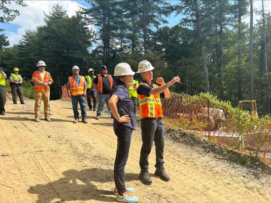 Secretary Haaland and group of people in safety vests and hard hats. 