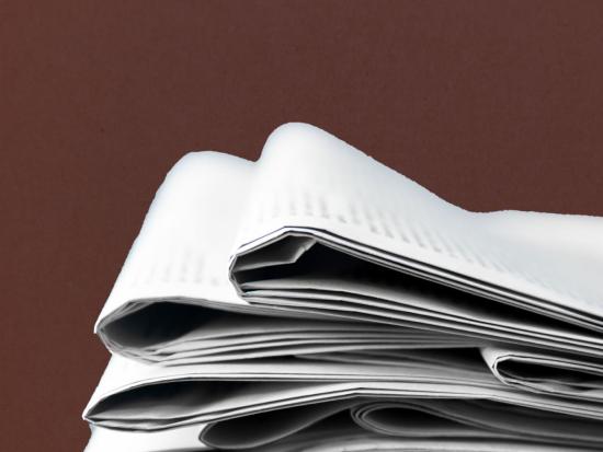 Stack of newspapers on a red background.