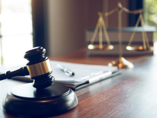 Image of a wooden office desk with a small scale and gavel.