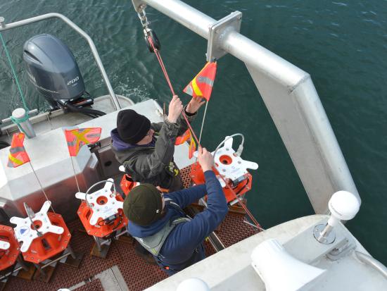 Two scientists on a boat, preparing to deploy siesmometers into the ocean. 