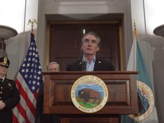 Secretary of the Interior Doug Burgum speaks from a podium surrounded by Interior Department staff