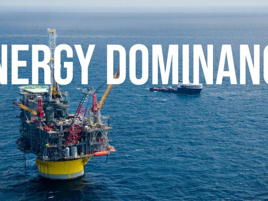 A yellow and gray offshore oil rig and boat are on the ocean with the text energy dominance