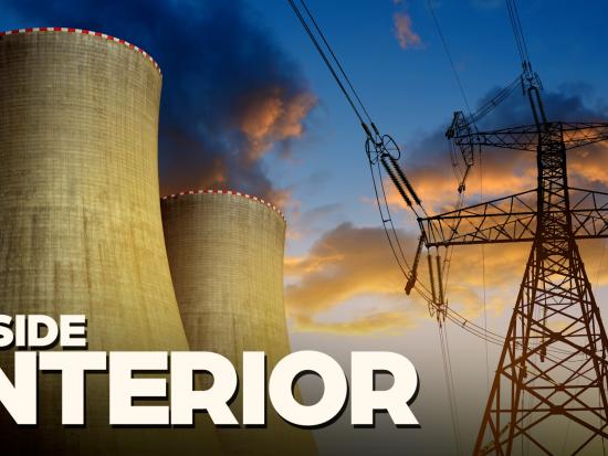 Evaporation towers and electrical lines under a blue and orange sky