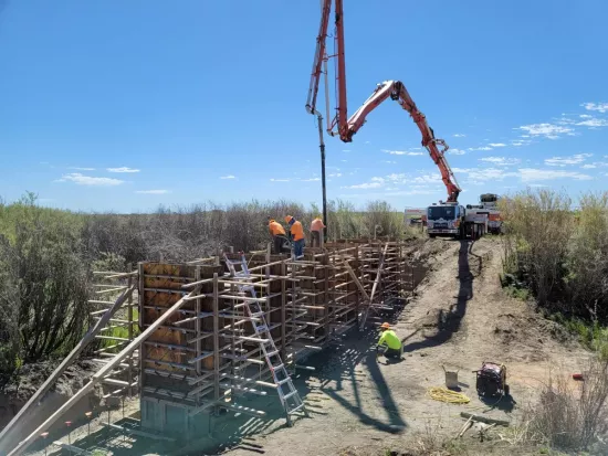 Construction workers on top of wooden structure with construction vehicle in the background