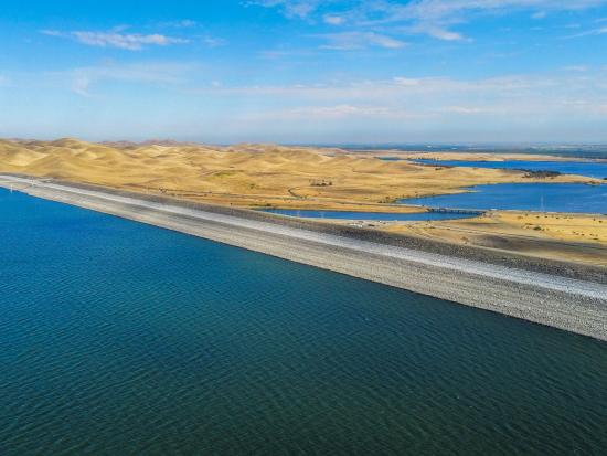 Expansive reservoir and dam with a cloudy blue sky