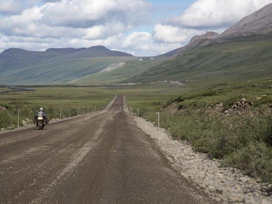 A motorcycle drives across the Dalton Highway in Alaska.