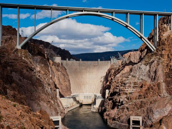 Hoover Dam and the bypass bridge under a partially-cloudy sky.