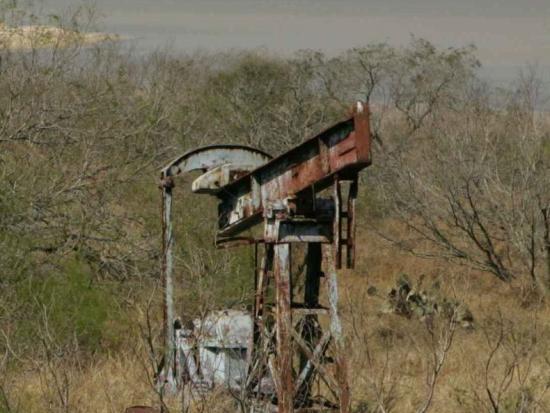 Abandoned gas well pump in prairie grasses. 