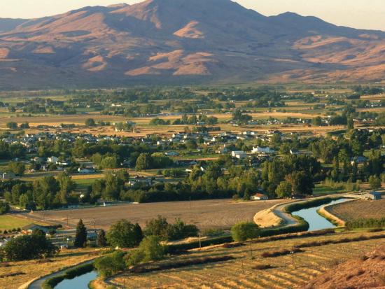 Field with a river and canal, mountains in the background.
