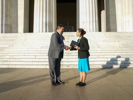 Director Chuck Sams and Secretary Deb Haaland shake hands in front of the Lincoln Memorial.
