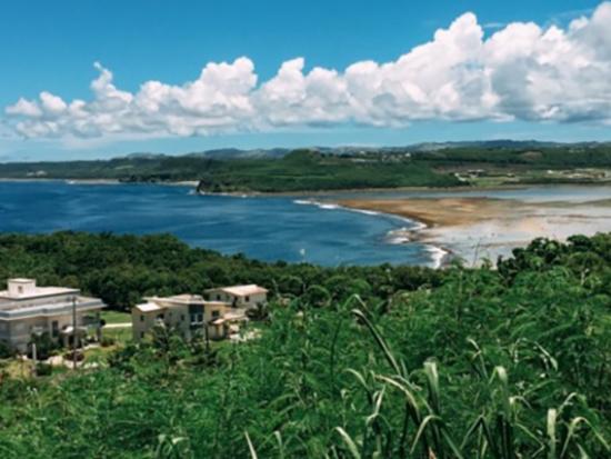 Tropical island landscape taken from a scenic vantage point showing blue ocean and cloudy blue skies