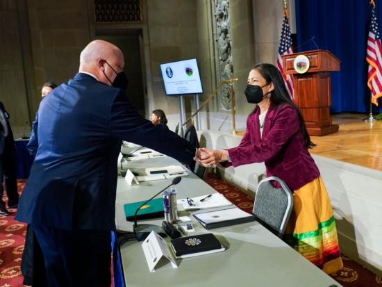 Secretary Haaland shakes hands across the table.