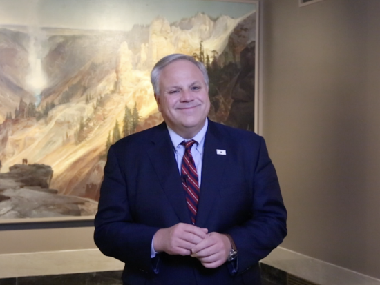 Secretary Bernhardt standing in front of a large painting of Yellowstone National Park.