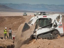 Excavator clears dirt as staff repairs a broken waterline