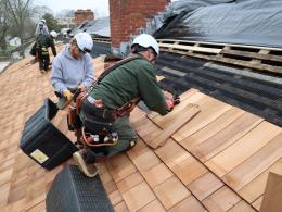 Workers lay panels on the roof of a building