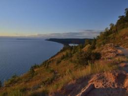 Green sloping coastline next to blue water