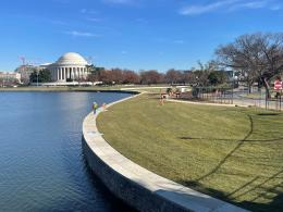 Body of water with walkway on the edge and a white building in the background