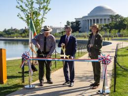 Secretary Burgum and two park rangers cutting red white and blue ribbon at ribbon cutting ceremony. 