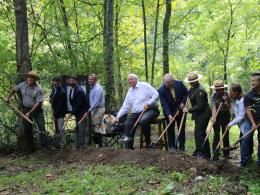 a line of people tossing dirt from shovels at a trailhead