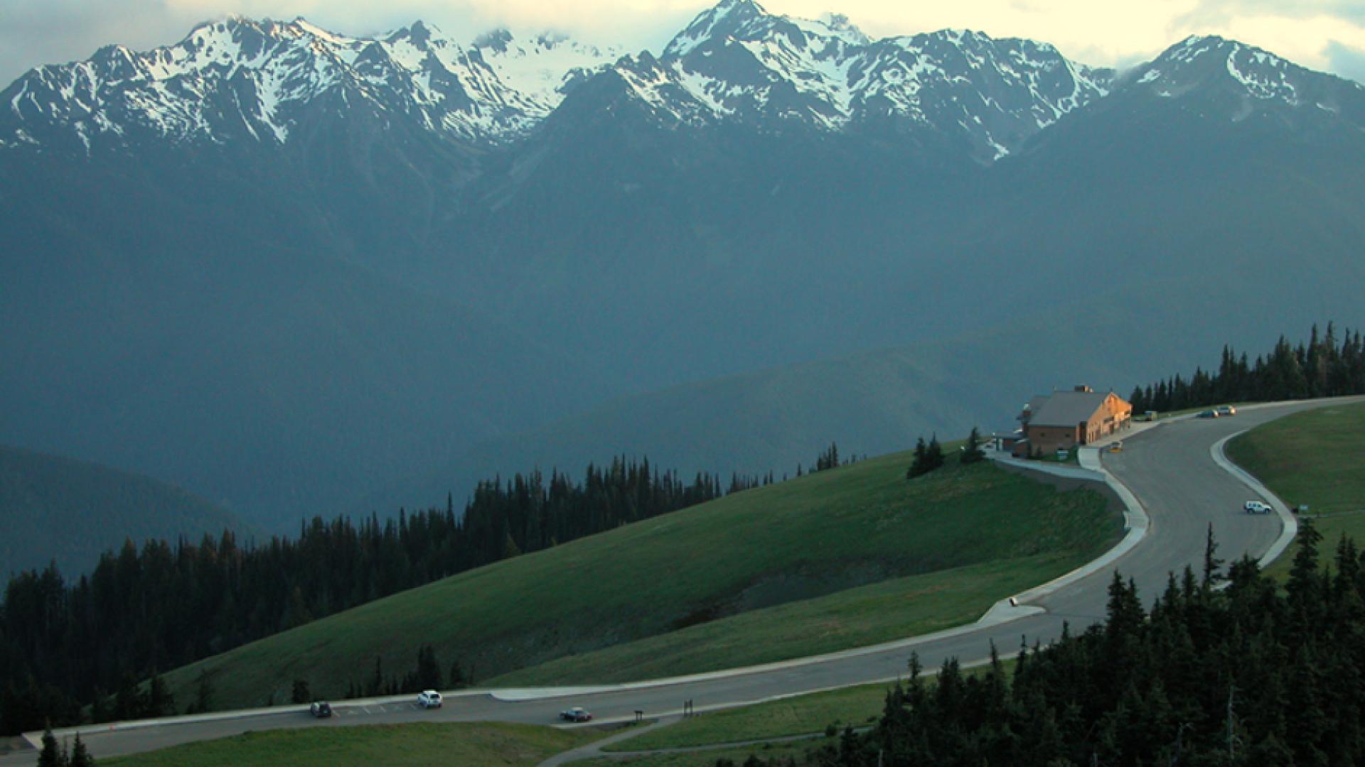 A view of the Hurricane Ridge Day Lodge from above, with the Olympic Mountains in the background