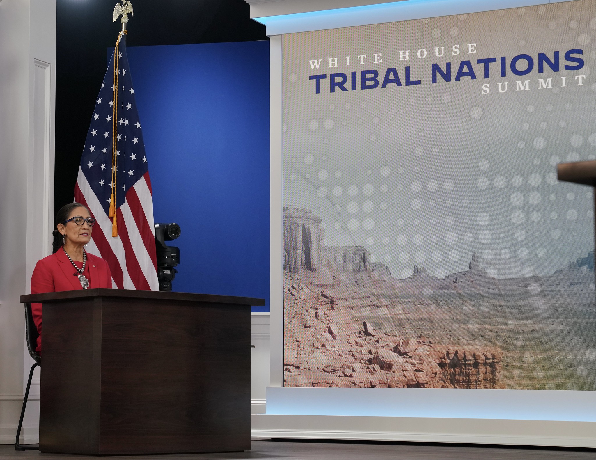Secretary Haaland sits in front of a sign that reads "Tribal Nations Summit"