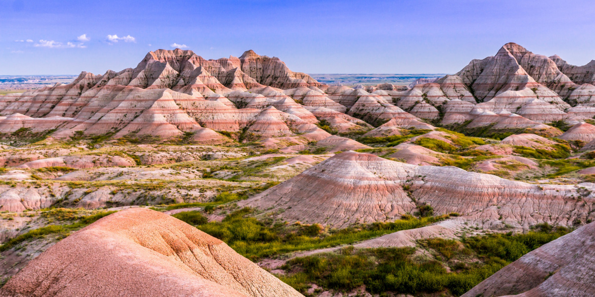 Layered badlands buttes reach into a clear blue sky above.